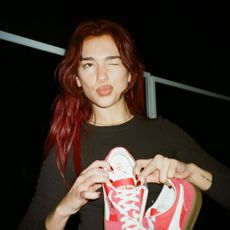 Dua Lipa holds up a pair of sneakers while rehearsing for an awards show
