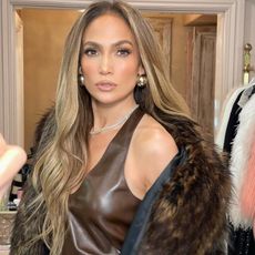 Jennifer Lopez wearing an all-brown outfit with a fur coat while posing in her closet