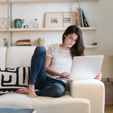 Woman on laptop on couch shopping for virtual gift 